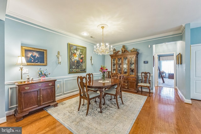 dining area with a chandelier, ornamental molding, light wood-type flooring, and baseboards