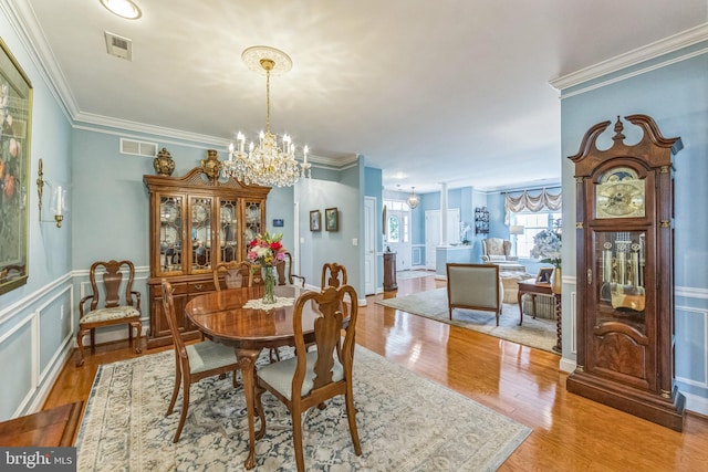 dining space with a chandelier, light wood-type flooring, and ornamental molding