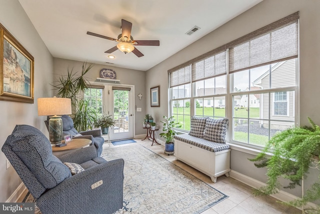 living room with healthy amount of natural light, baseboards, ceiling fan, and light tile patterned floors