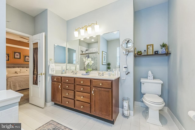 full bath with a stall shower, tile patterned flooring, double vanity, ensuite bath, and baseboards