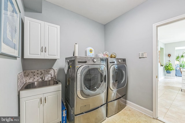 washroom with cabinet space, washing machine and clothes dryer, baseboards, and light tile patterned flooring