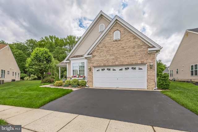 traditional-style house featuring brick siding, driveway, a front yard, and a garage
