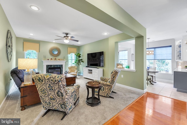 living area with baseboards, light wood-style floors, healthy amount of natural light, a premium fireplace, and recessed lighting