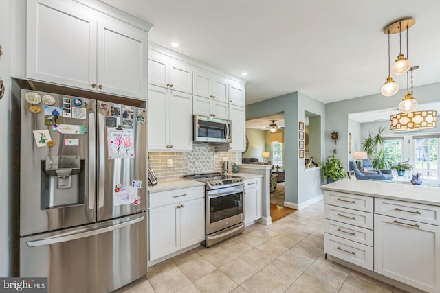 kitchen featuring stainless steel appliances, light countertops, decorative backsplash, light tile patterned floors, and white cabinetry