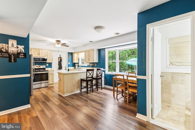 11500 Acton Ln, Waldorf, MD 20601 - kitchen with appliances with stainless steel finishes, a peninsula, light countertops, dark wood-type flooring, and a kitchen bar