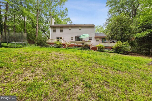 11500 Acton Ln, Waldorf, MD 20601 - back of house featuring a trampoline, a deck, a chimney, and a lawn