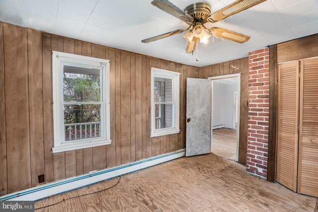 611-615 S New York Rd, Absecon, NJ 08205 - unfurnished bedroom with a baseboard heating unit, wooden walls, a closet, ceiling fan, and wood finished floors