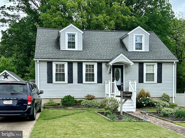 new england style home featuring a front lawn, a shingled roof, and view of scattered trees