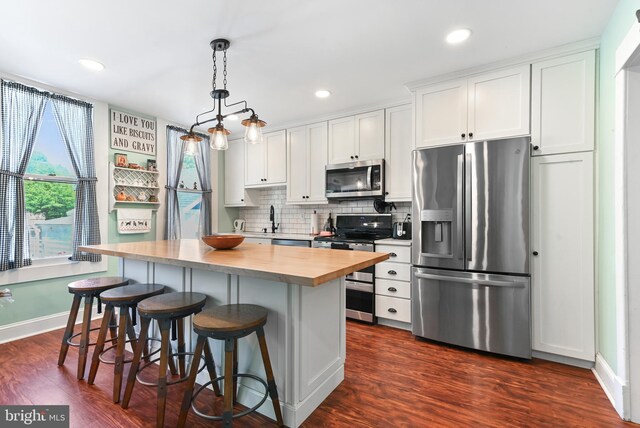 714 W St, Laurel, DE 19956 - kitchen featuring appliances with stainless steel finishes, white cabinets, a center island, dark wood-type flooring, and backsplash