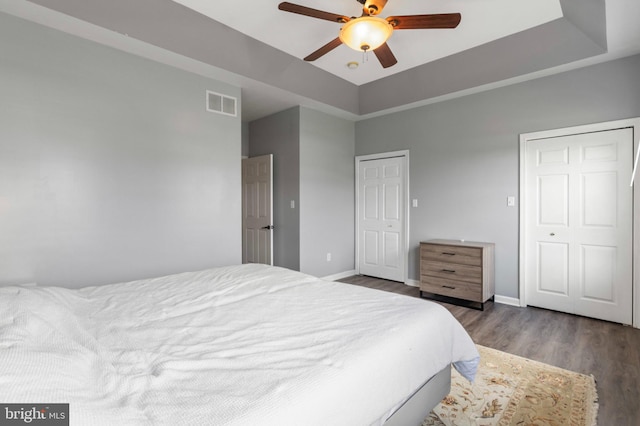 bedroom featuring wood finished floors, baseboards, a raised ceiling, and a ceiling fan