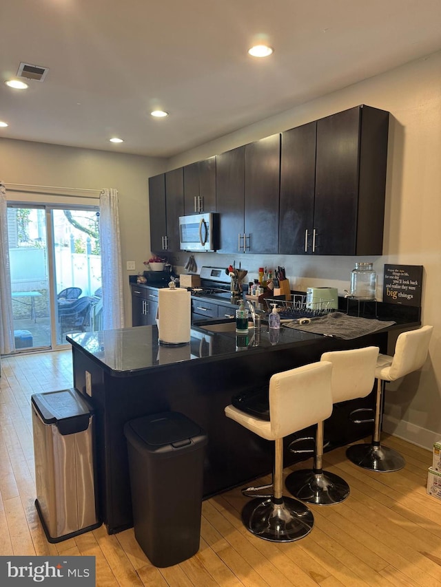 641 N 12th St, Philadelphia, PA 19123 - kitchen with stainless steel appliances, light wood finished floors, a breakfast bar area, dark countertops, and recessed lighting