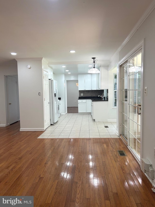 8524 Betterton Ct, Vienna, VA 22182 - kitchen with white fridge with ice dispenser, light wood-style floors, dark countertops, white cabinets, and ornamental molding