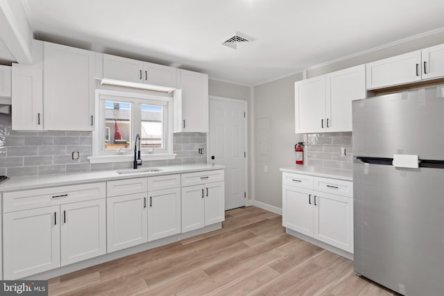 341 Ives Ave, Penns Grove, NJ 08069 - kitchen with freestanding refrigerator, a sink, light countertops, white cabinetry, and backsplash