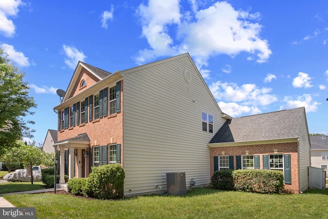 16874 Reef Knot Way, Woodbridge, VA 22191 - view of property exterior featuring brick siding, a lawn, and central AC unit