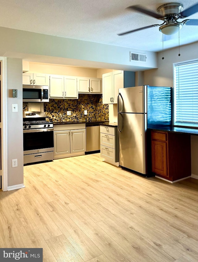 1836 Metzerott Rd Unit 1414, Adelphi, MD 20783 - kitchen with stainless steel appliances, dark countertops, a ceiling fan, light wood-style flooring, and decorative backsplash
