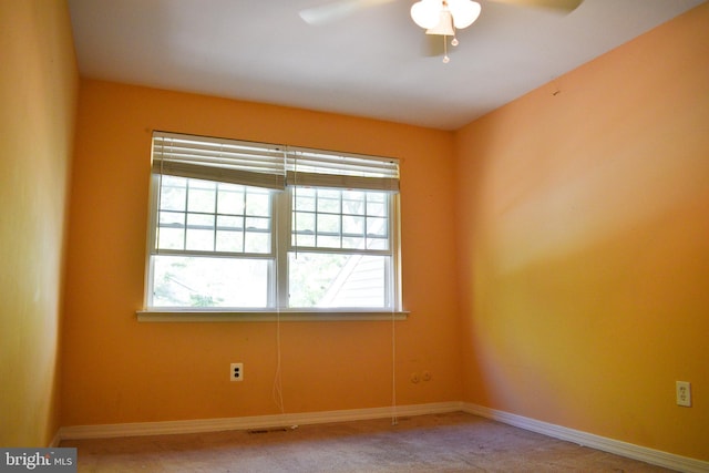 carpeted empty room with a ceiling fan and baseboards