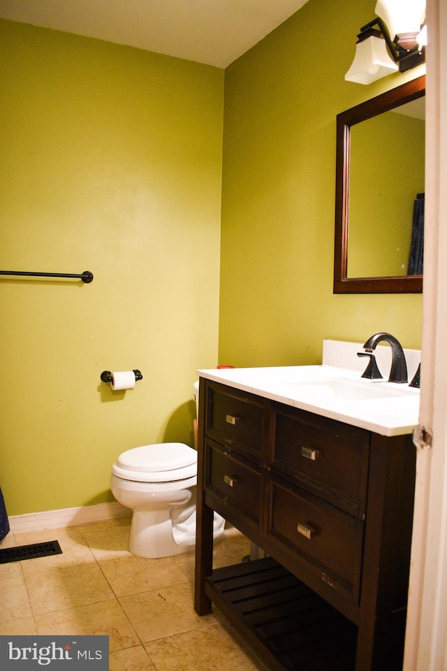 half bathroom with toilet, vanity, and baseboards