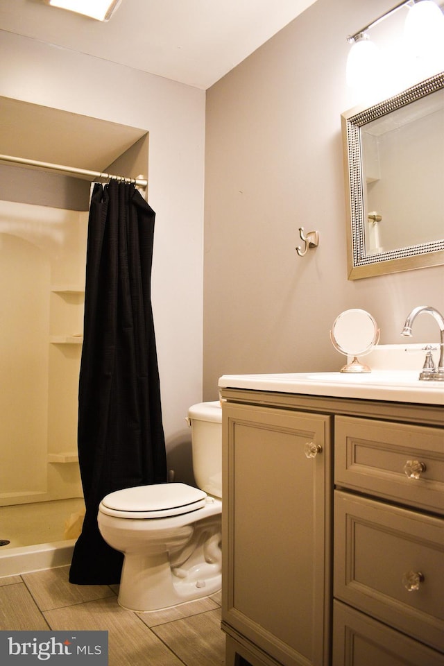 bathroom featuring toilet, a shower with shower curtain, vanity, and wood finished floors