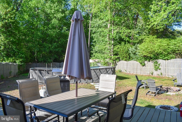 deck featuring an outdoor fire pit, a fenced backyard, and outdoor dining space
