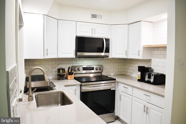 kitchen featuring stainless steel appliances, white cabinets, tasteful backsplash, and a sink