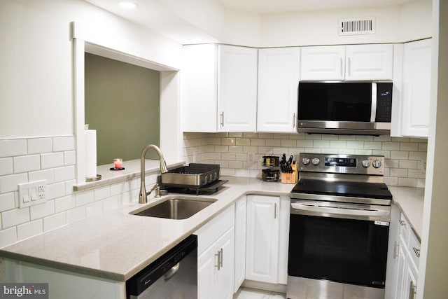 kitchen with appliances with stainless steel finishes, a sink, white cabinets, and backsplash