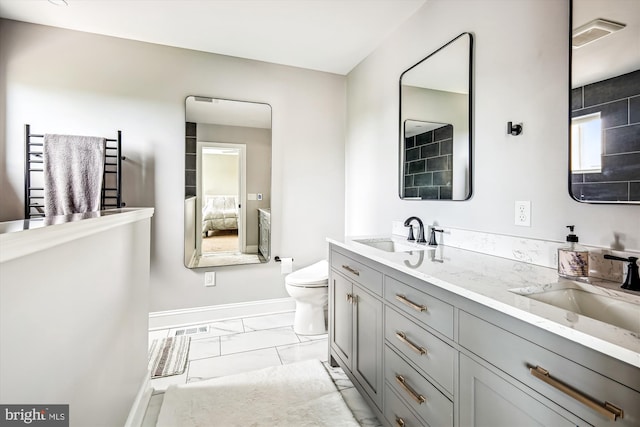 2006 N Bancroft Pkwy, Wilmington, DE 19806 - full bathroom with marble look tiles, baseboards, double vanity, toilet, and a towel warming rack