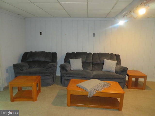 carpeted living room with a drop ceiling and wooden walls