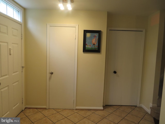 foyer featuring light tile patterned flooring and baseboards