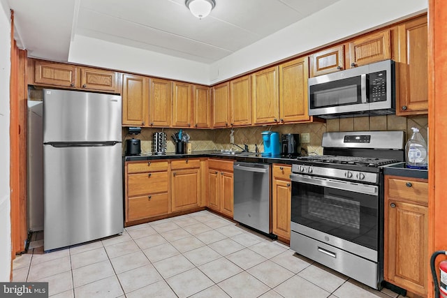 10816 Green Mountain Cir Unit 19-10, Columbia, MD 21044 - kitchen with appliances with stainless steel finishes, dark countertops, brown cabinets, backsplash, and light tile patterned floors