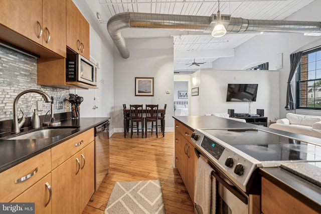 200 Lincoln Ave Unit 304, Phoenixville, PA 19460 - kitchen with stainless steel appliances, a sink, light wood-style floors, backsplash, and dark countertops