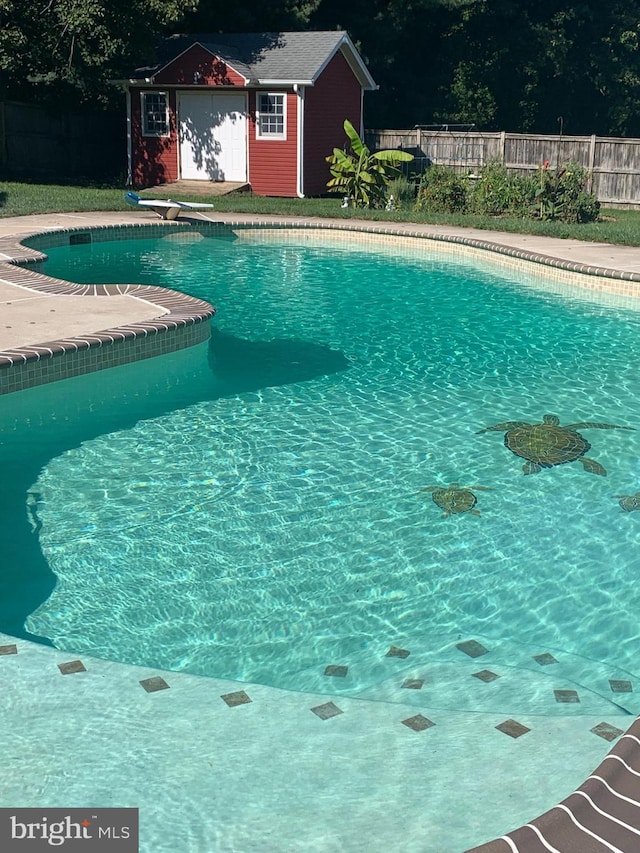 view of swimming pool featuring fence, an outdoor structure, a diving board, and a storage shed