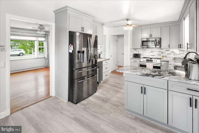 101 Flower, Mount Airy, MD 21771 - kitchen with stainless steel appliances, a ceiling fan, decorative backsplash, light wood finished floors, and light stone counters