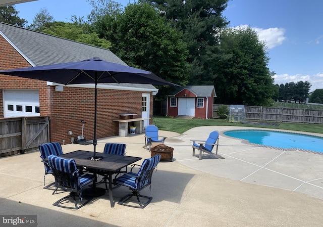 view of pool with a fire pit, a patio, a fenced backyard, and a storage unit