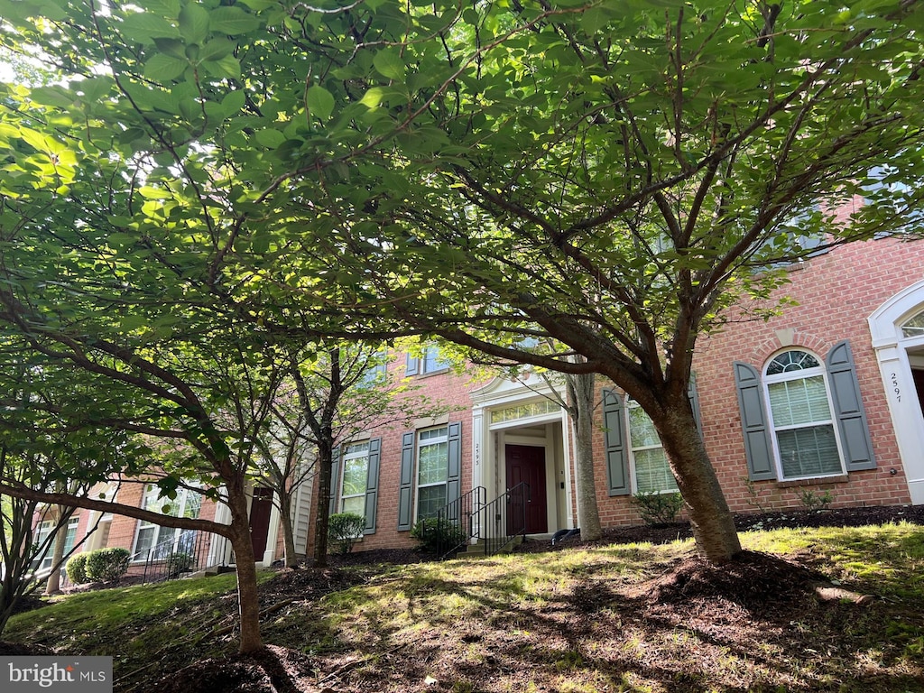 view of property hidden behind natural elements with brick siding
