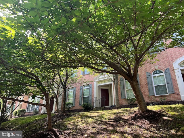 view of property hidden behind natural elements with brick siding