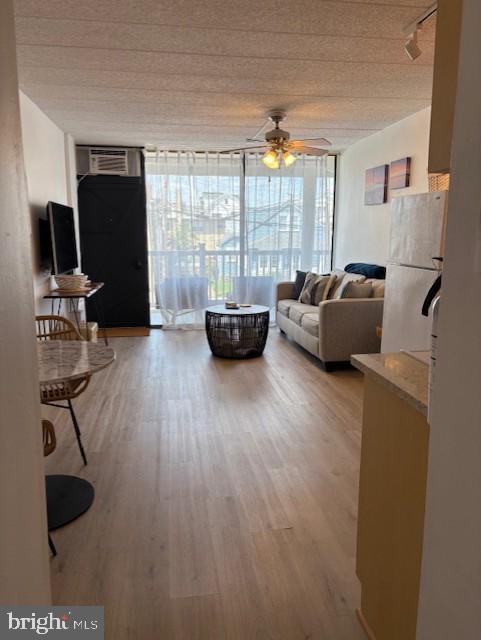 9415 Pacific Ave Unit 43, Margate City, NJ 08402 - living room with wood finished floors, expansive windows, a ceiling fan, and a wall mounted air conditioner