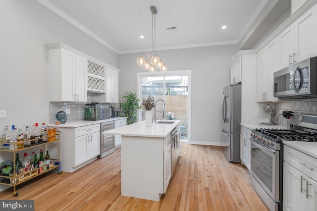 kitchen featuring appliances with stainless steel finishes, beverage cooler, a sink, a center island with sink, and light countertops
