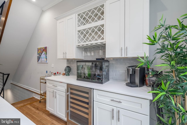 indoor bar with wine cooler, backsplash, light wood finished floors, and baseboards
