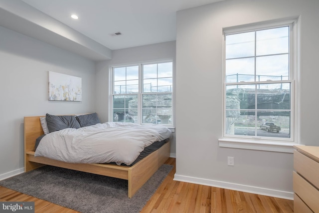 bedroom with light wood-style floors, multiple windows, baseboards, and recessed lighting