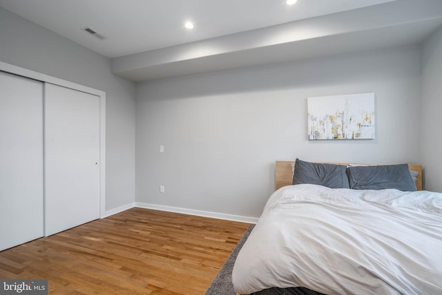 bedroom featuring wood finished floors, baseboards, recessed lighting, and a closet