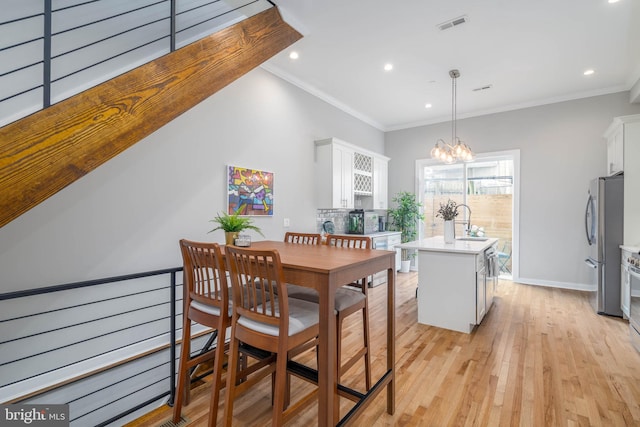 dining area featuring light wood-type flooring, recessed lighting, a chandelier, baseboards, and ornamental molding