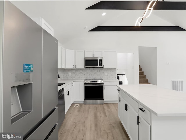 kitchen with stainless steel appliances, white cabinets, backsplash, light wood-type flooring, and light countertops