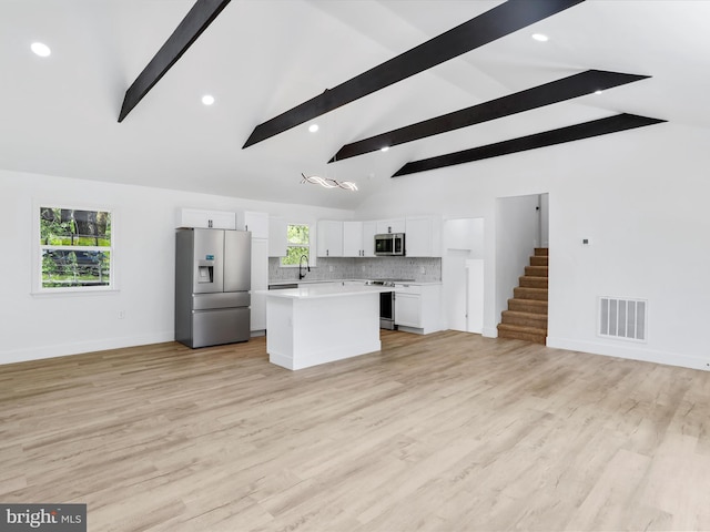 kitchen featuring appliances with stainless steel finishes, light countertops, a kitchen island, white cabinets, and open floor plan
