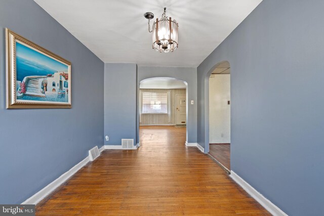 6602 Revere St, Philadelphia, PA 19149 - corridor featuring arched walkways, a chandelier, wood finished floors, and baseboards