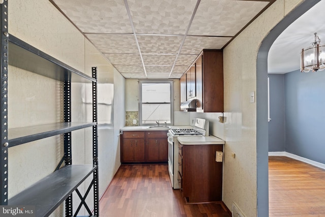 6602 Revere St, Philadelphia, PA 19149 - kitchen with white gas stove, a sink, dark wood-style floors, light countertops, and arched walkways