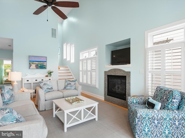 32561 Heron Cir Unit 13, Bethany Beach, DE 19930 - living room with a towering ceiling, ceiling fan, a glass covered fireplace, baseboards, and stairway