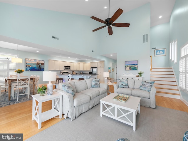 32561 Heron Cir Unit 13, Bethany Beach, DE 19930 - living room with light wood-type flooring, high vaulted ceiling, plenty of natural light, a ceiling fan, and stairs