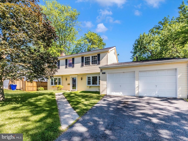 colonial home featuring asphalt driveway, an attached garage, and a chimney