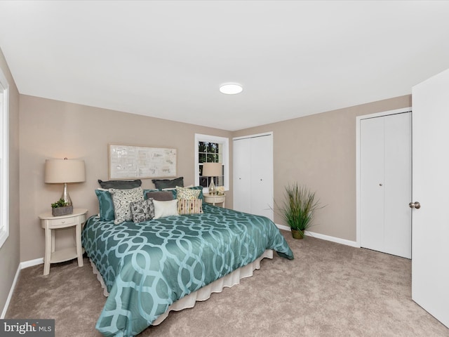 bedroom featuring baseboards, carpet floors, and two closets