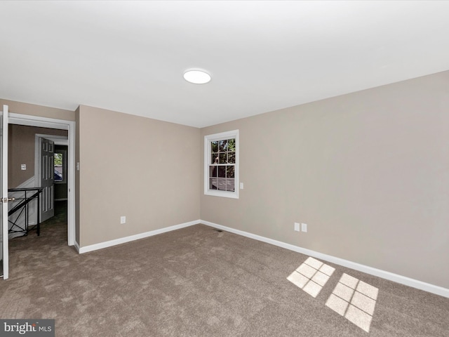 unfurnished room with carpet and baseboards